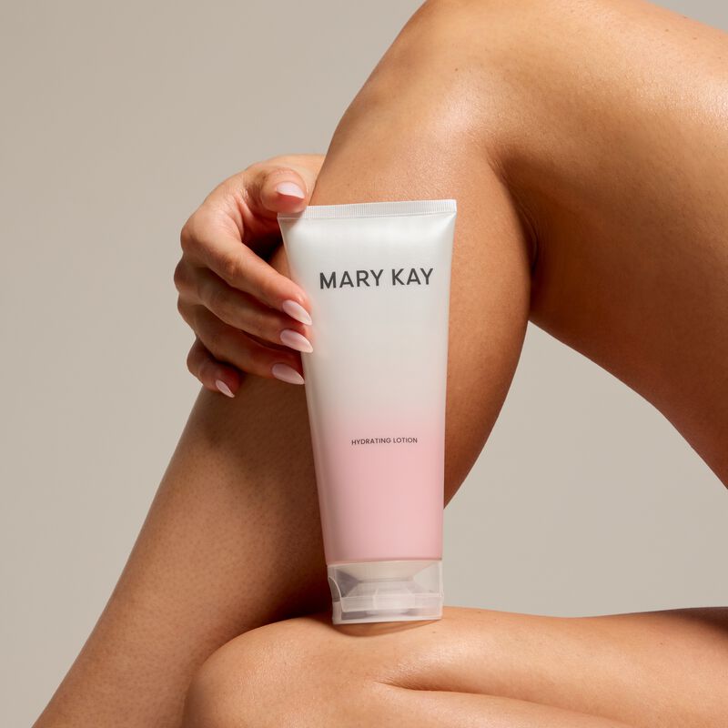 Mary Kay Hydrating Lotion tube held beside bent legs against a neutral background