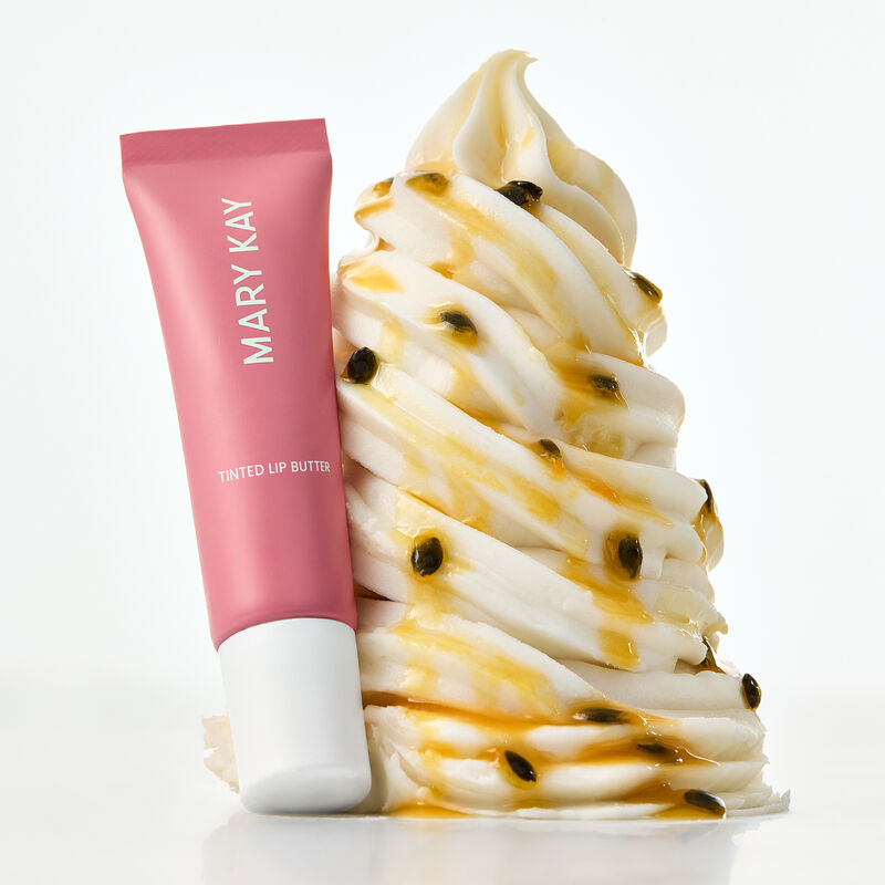 Tinted Lip Butter in Passionfruit Kiss styled against whipped cream with syrup and seeds NOTE Food images are for illustrative purposes only
