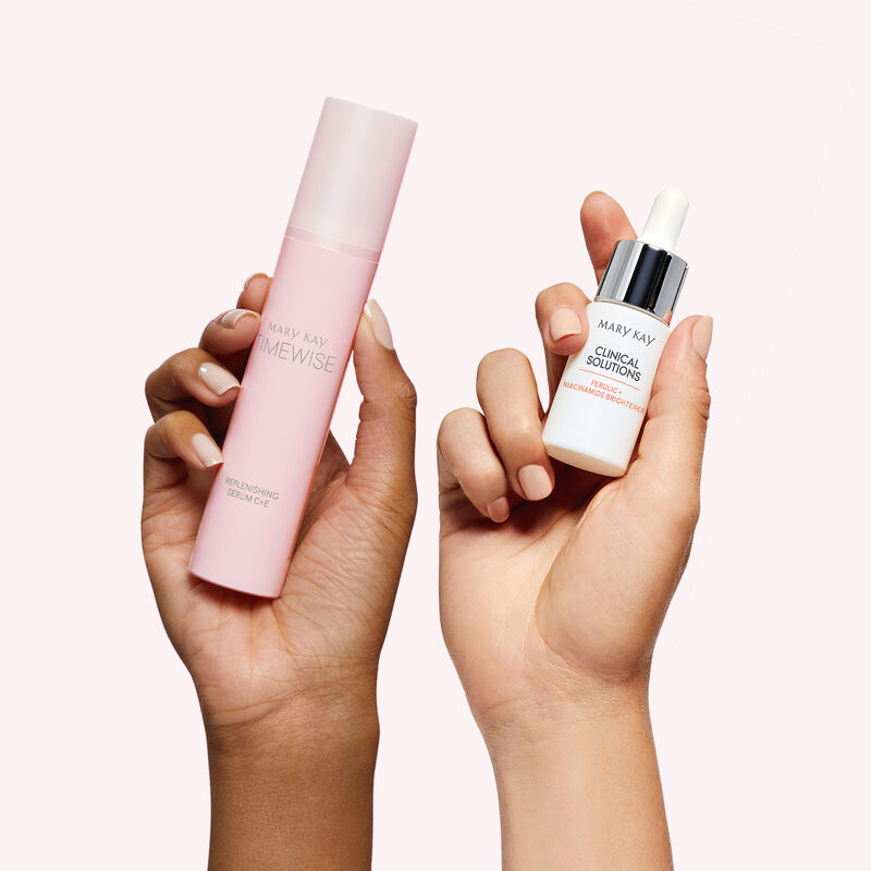 Two hands of contrasting skin tones each holding a bottle from the limited-edition Best in Brightness Bundle against light pink background