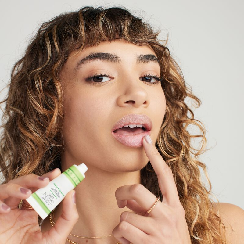 Modelo aplic&aacute;ndose White Tea & Citrus Satin Lips Shea Sugar Scrub en los labios con el dedo