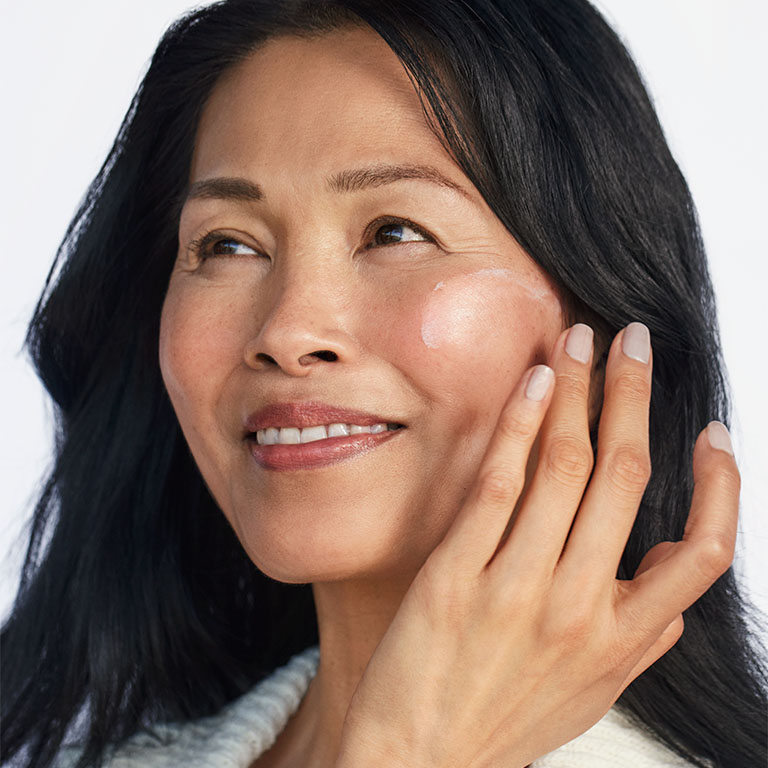 Model applying Mary Kay Sunscreen Broad Spectrum SPF 50 to her cheek