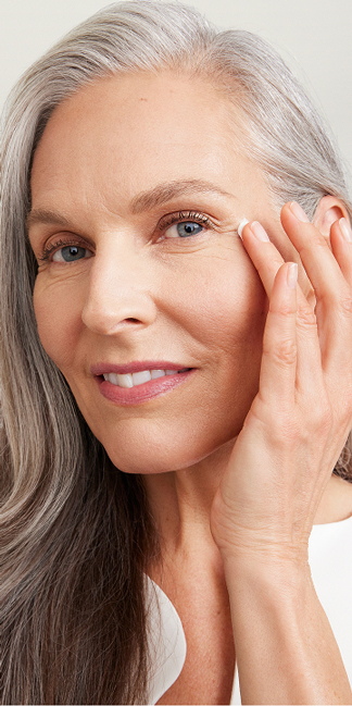 Woman with radiant mature skin applying eye cream